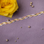A close-up image of a sterling silver bracelet with a fishtail braid pattern, displayed on a textured background with a yellow flower and pearls scattered around.