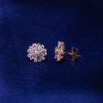 A pair of sterling silver earrings with a rose gold color finish, featuring floral embellishments on a blue background.