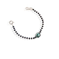 A sterling silver bracelet for kids featuring a green heart charm and black and white beads.