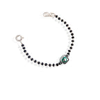 A sterling silver bracelet for kids featuring a green heart charm and black and white beads.