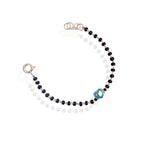 A sterling silver bracelet for kids featuring a green heart charm and black and white bead details.