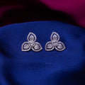 A pair of sterling silver stud earrings with an embellished leaflet design, displayed on a blue fabric.
