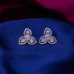 A pair of sterling silver stud earrings with an embellished leaflet design, displayed on a blue fabric.
