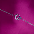 A multicolor Selene charm bracelet with a silver rhodium-based coating, displayed on a pink background.