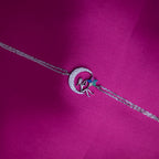 A multicolor Selene charm bracelet with a silver rhodium-based coating, displayed on a pink background.