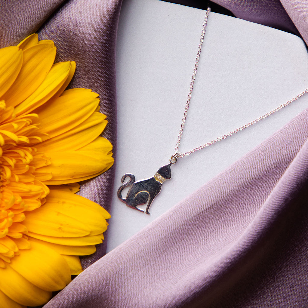 A silver pendant chain featuring a cat design, displayed on a flower-shaped background.