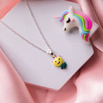 A sterling silver pendant chain featuring a yellow teddy bear with a green apple, displayed on a pink background.