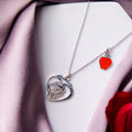 A silver-colored pendant chain necklace featuring a silhouette of Snow White within a heart-shaped frame, displayed on a white base with a purple scarf.