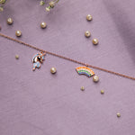 A sterling silver charm bracelet with rose golden and multi-colored charms, including a unicorn and a rainbow, displayed on a purple background with pearl accents.