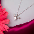 A silver pendant chain necklace with a reindeer antlers motif and a solitaire gemstone, displayed against a white and pink background.